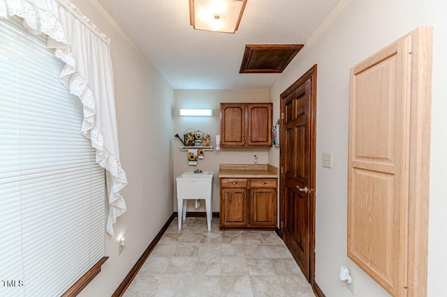 clothes washing area with cabinets, a textured ceiling, and a wealth of natural light