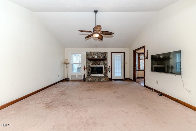 unfurnished living room featuring carpet flooring, ceiling fan, a stone fireplace, and vaulted ceiling