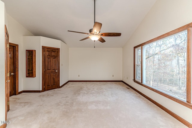 empty room featuring light colored carpet, vaulted ceiling, and ceiling fan