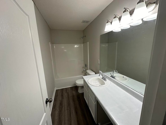 full bathroom featuring vanity, a textured ceiling,  shower combination, wood-type flooring, and toilet