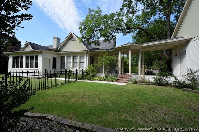 rear view of house with a lawn and a porch