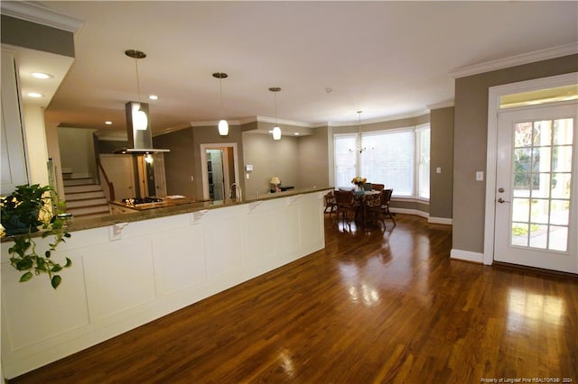 kitchen with stone counters, dark hardwood / wood-style floors, crown molding, pendant lighting, and island range hood