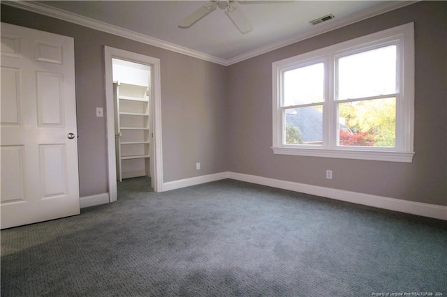 unfurnished bedroom with carpet floors, a spacious closet, ceiling fan, and crown molding