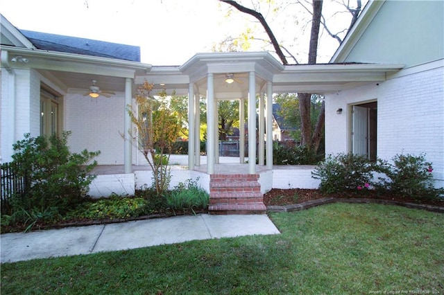 entrance to property featuring ceiling fan and a lawn