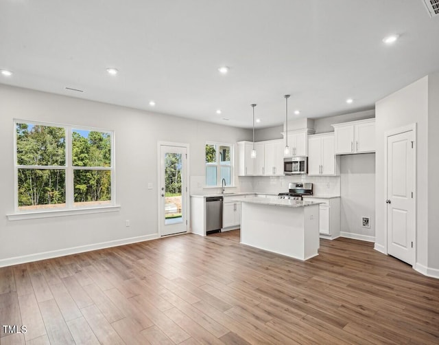 kitchen with pendant lighting, a center island, white cabinetry, and stainless steel appliances