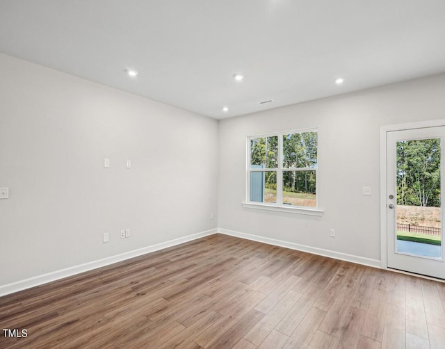 spare room featuring a wealth of natural light and light hardwood / wood-style flooring