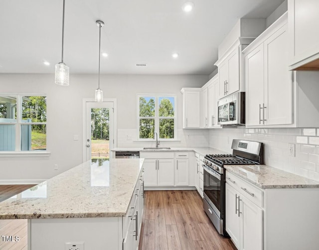 kitchen with a center island, stainless steel appliances, white cabinetry, and sink