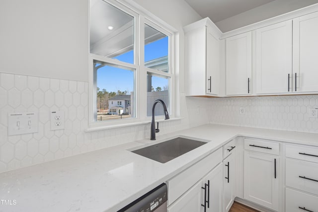 kitchen featuring backsplash, white cabinetry, light stone counters, and a sink