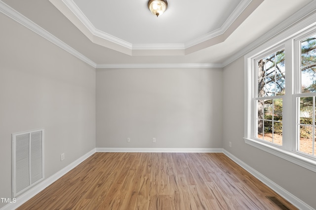 spare room featuring a tray ceiling, light hardwood / wood-style floors, and ornamental molding