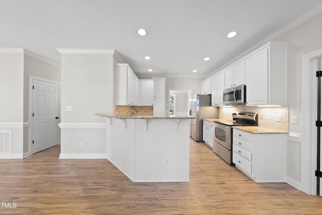 kitchen featuring light stone countertops, white cabinetry, light wood-type flooring, and appliances with stainless steel finishes