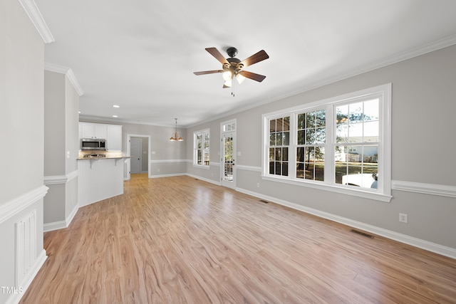 unfurnished living room featuring light wood-type flooring, crown molding, and a healthy amount of sunlight