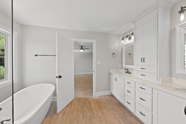 bathroom with hardwood / wood-style flooring, a washtub, ceiling fan, and vanity