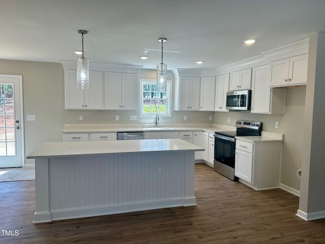 kitchen with a sink, a kitchen island, dark wood-style floors, white cabinetry, and appliances with stainless steel finishes