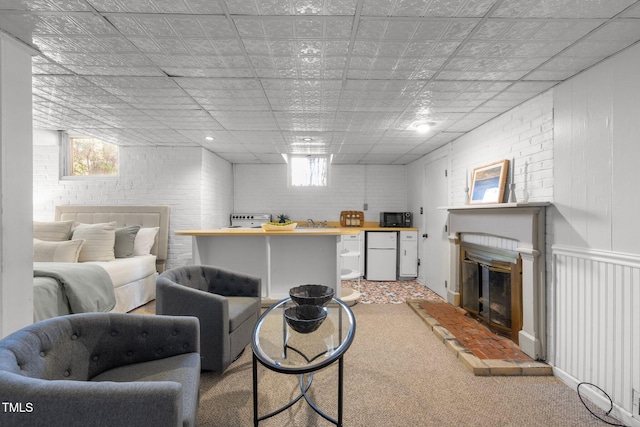 carpeted living room with brick wall and sink