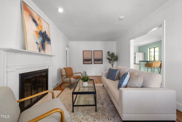 living room with crown molding, a brick fireplace, and light wood-type flooring