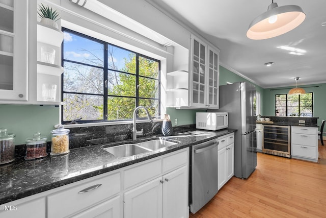 kitchen featuring sink, decorative light fixtures, stainless steel appliances, and beverage cooler