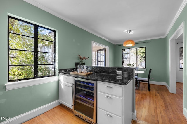 kitchen featuring white cabinetry, hanging light fixtures, wine cooler, kitchen peninsula, and dark stone counters