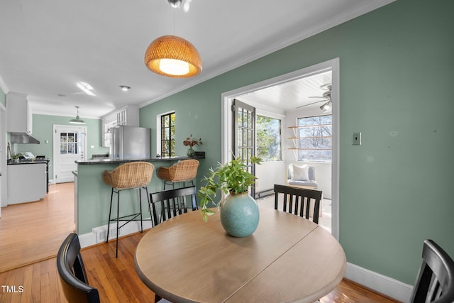 dining room with ornamental molding, ceiling fan, and light hardwood / wood-style floors