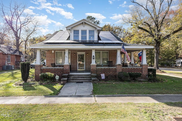 view of front of property with a front yard, solar panels, and a porch