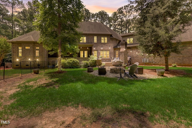 back house at dusk featuring a fire pit and a yard