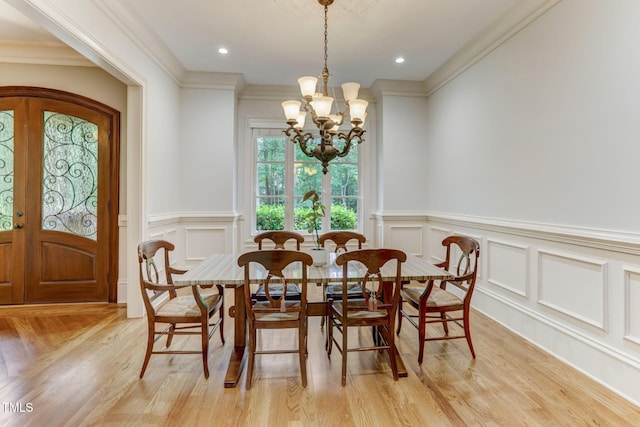 dining space with crown molding, light hardwood / wood-style floors, a chandelier, and french doors