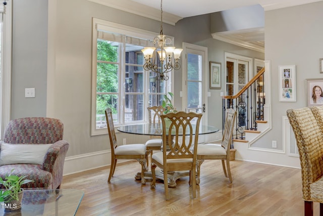 dining area featuring light wood-type flooring, a wealth of natural light, crown molding, and an inviting chandelier