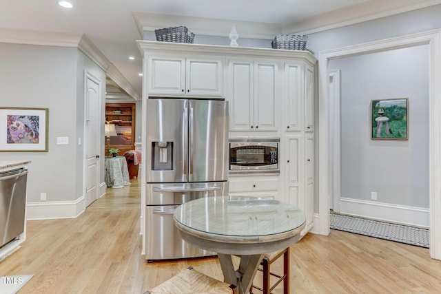 kitchen featuring white cabinets, light wood-type flooring, ornamental molding, and appliances with stainless steel finishes