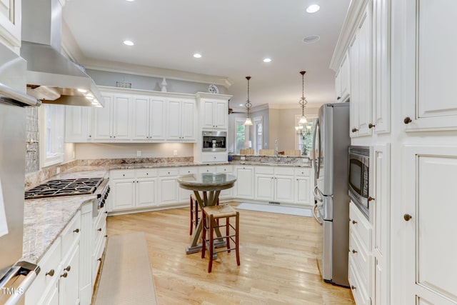 kitchen with decorative light fixtures, white cabinetry, light stone counters, and island range hood