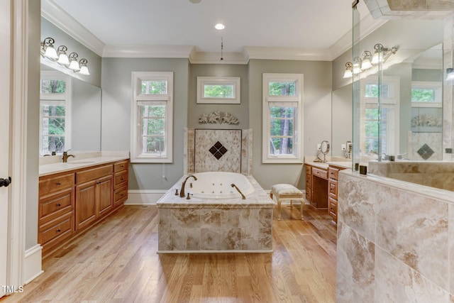 bathroom with wood-type flooring, tiled tub, vanity, and ornamental molding