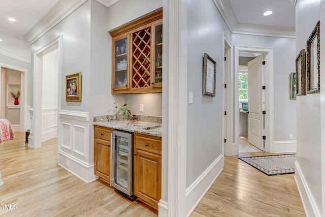 bar featuring light stone countertops, light wood-type flooring, ornamental molding, and wine cooler