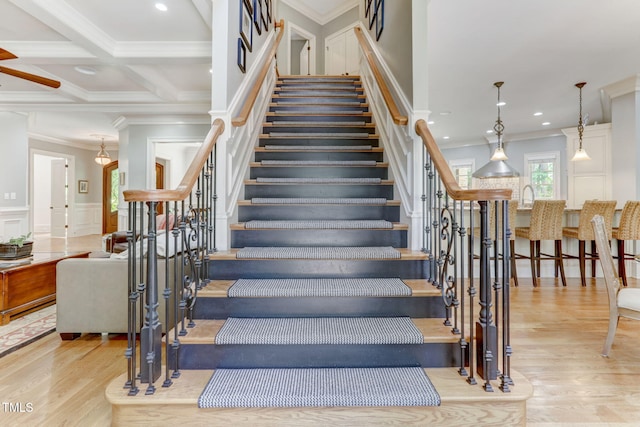 stairway featuring wood-type flooring, coffered ceiling, beam ceiling, and ornamental molding