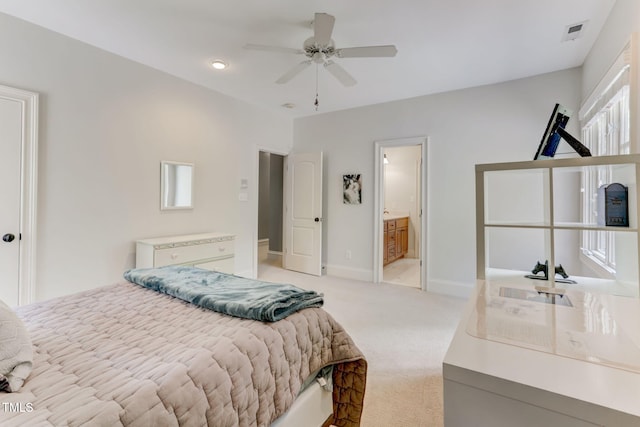 bedroom featuring ceiling fan, light colored carpet, and connected bathroom