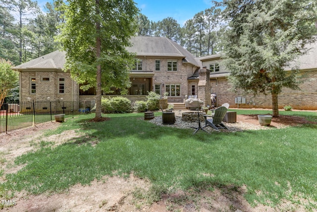 back of property with a yard and a fire pit