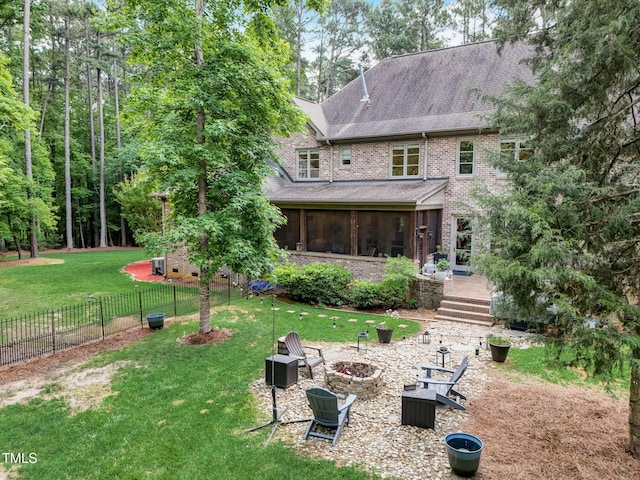 rear view of property featuring a sunroom, an outdoor fire pit, and a yard