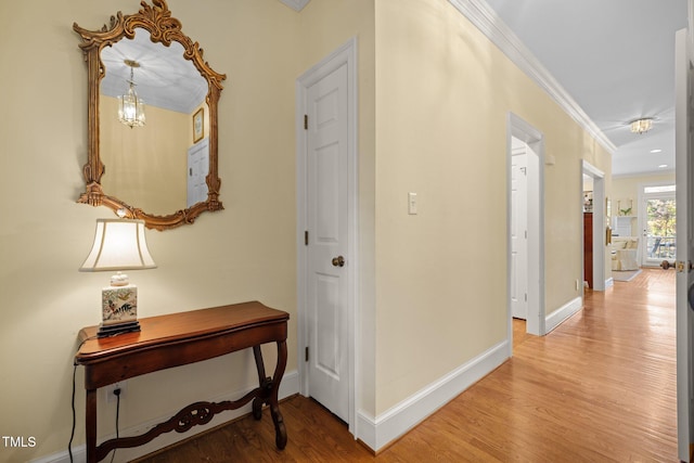 hallway with hardwood / wood-style floors, crown molding, and a chandelier