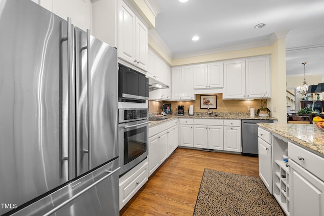 kitchen featuring white cabinetry, stainless steel appliances, light stone counters, light hardwood / wood-style floors, and ornamental molding