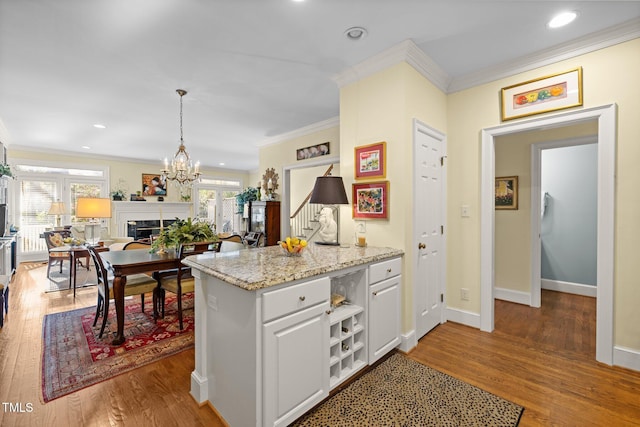 kitchen featuring white cabinetry, dark wood-type flooring, hanging light fixtures, and ornamental molding