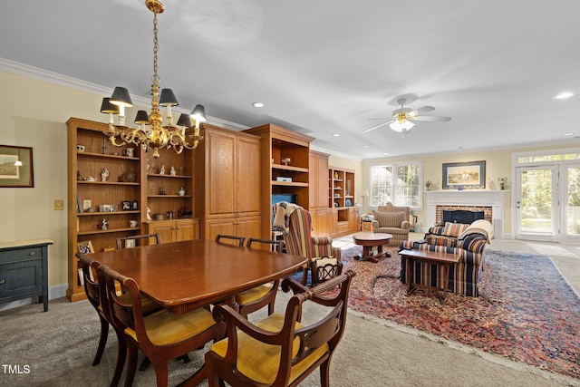 dining space with a fireplace, light carpet, ceiling fan with notable chandelier, and ornamental molding