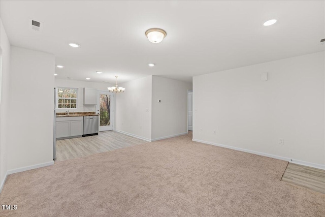 unfurnished living room with light carpet, sink, and a chandelier