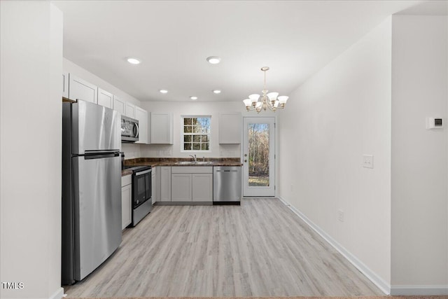 kitchen with light hardwood / wood-style floors, white cabinetry, sink, and appliances with stainless steel finishes