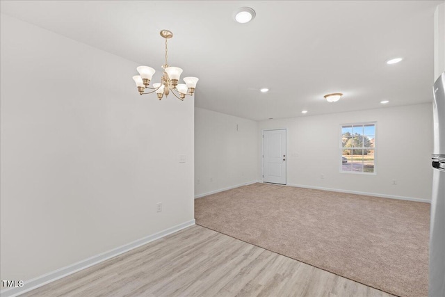 empty room with light hardwood / wood-style floors and a notable chandelier