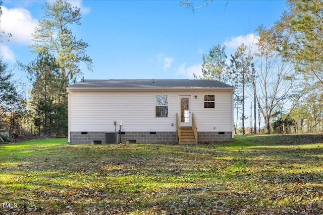 rear view of house with central AC unit and a lawn