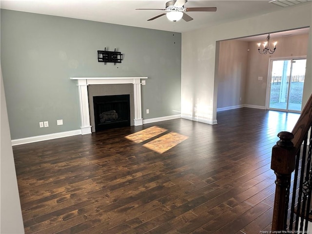 unfurnished living room with ceiling fan with notable chandelier and dark hardwood / wood-style flooring