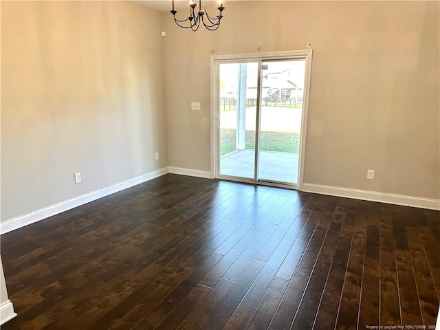 empty room with dark hardwood / wood-style flooring and a chandelier