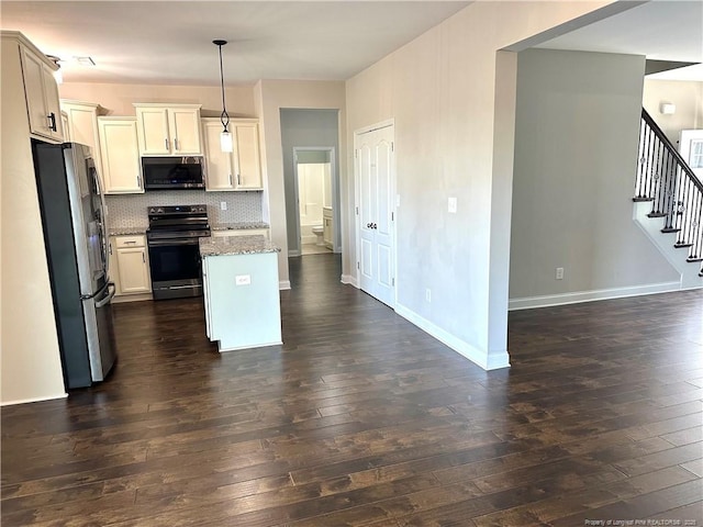 kitchen featuring backsplash, dark stone counters, hanging light fixtures, dark hardwood / wood-style floors, and stainless steel appliances