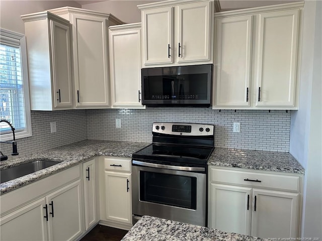 kitchen featuring backsplash, white cabinetry, sink, and appliances with stainless steel finishes