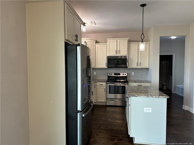 kitchen featuring tasteful backsplash, light stone counters, pendant lighting, white cabinets, and appliances with stainless steel finishes