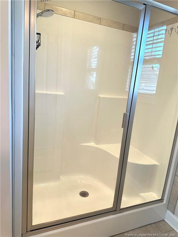 bathroom featuring tile patterned floors and a shower with shower door