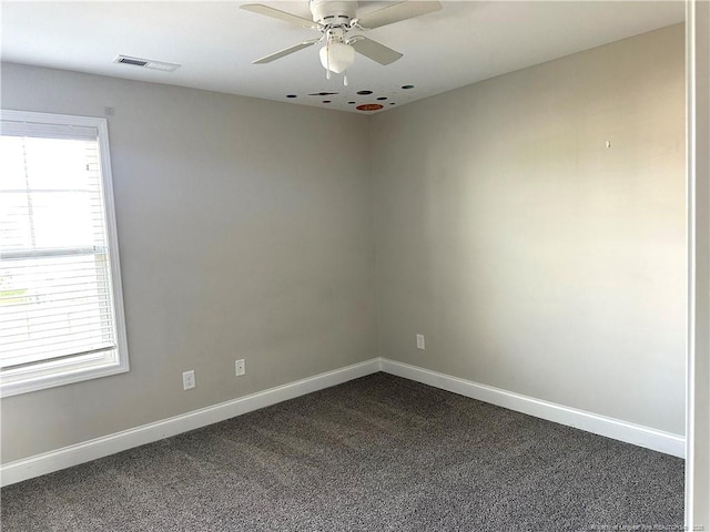 spare room with dark colored carpet and ceiling fan