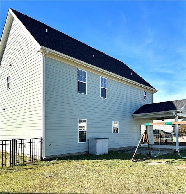 back of property featuring a playground and a lawn